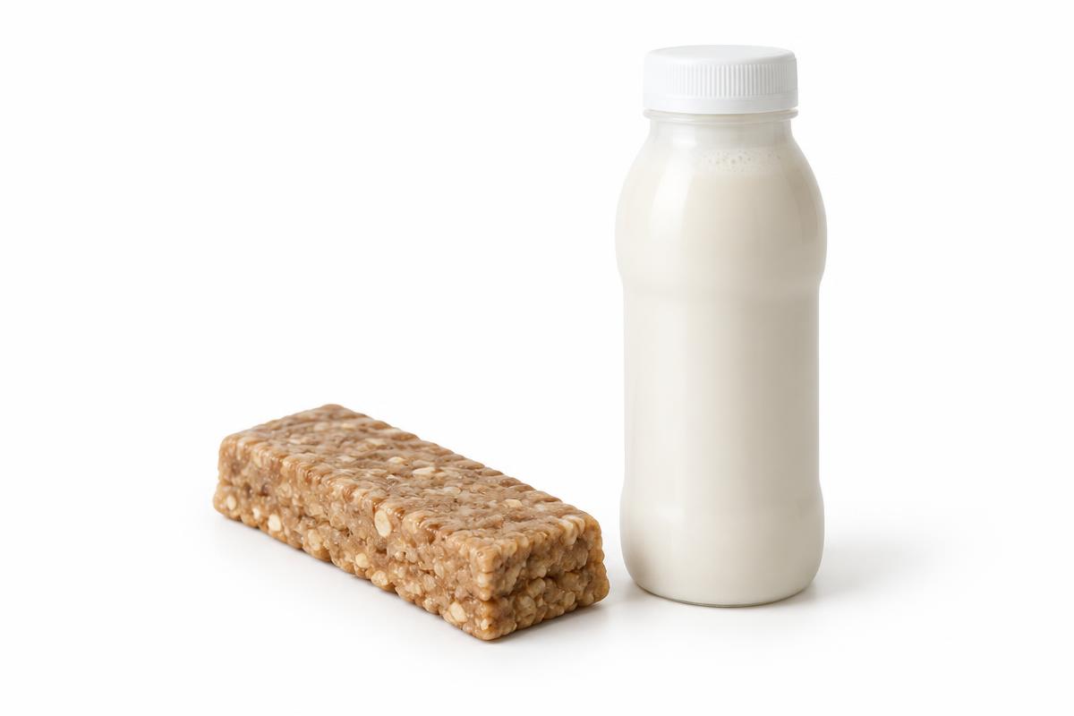 A protein bar next to a bottled protein shake on a white background